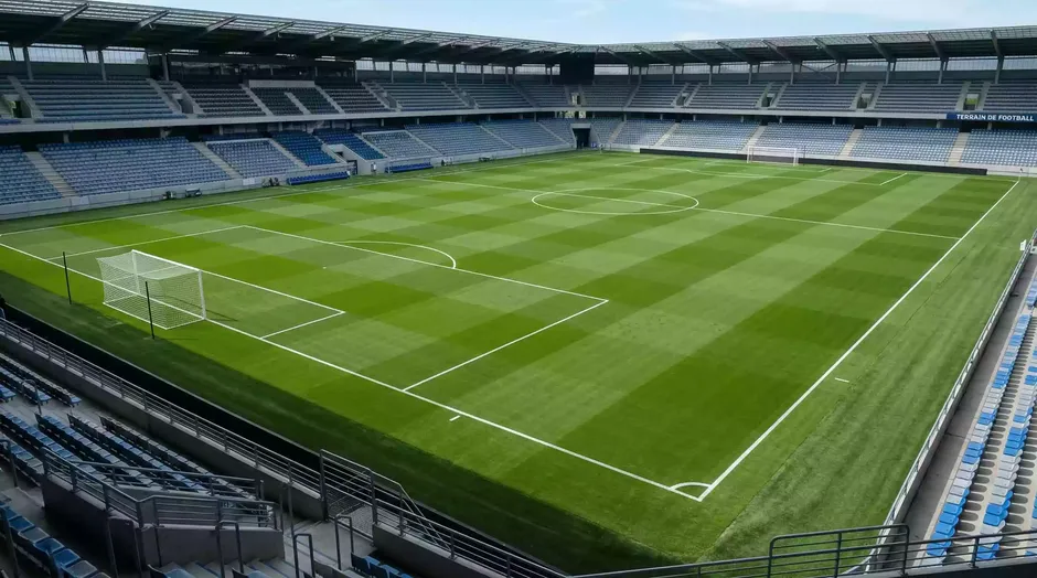 Terrain de football professionnel avec gazon vert et lignes blanches vu depuis les tribunes
